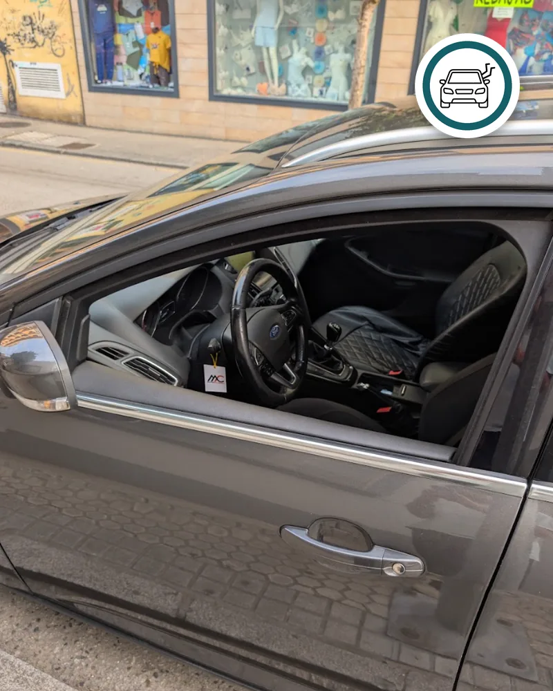 Coche gris aparcado y cerrado, con la ventanilla del conductor bajada del todo